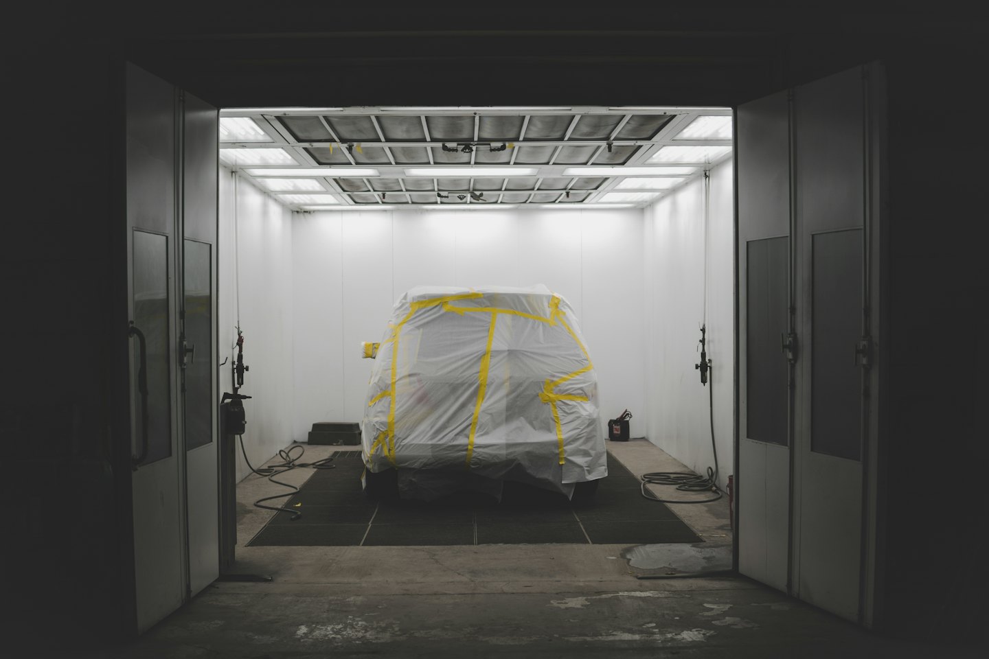 Auto in einer Lackierkabine unter einer Plastikfolie.